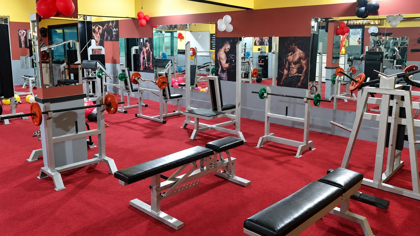 The New Gold Gym training floor with red flooring, benches, mirrors and strength equipment.