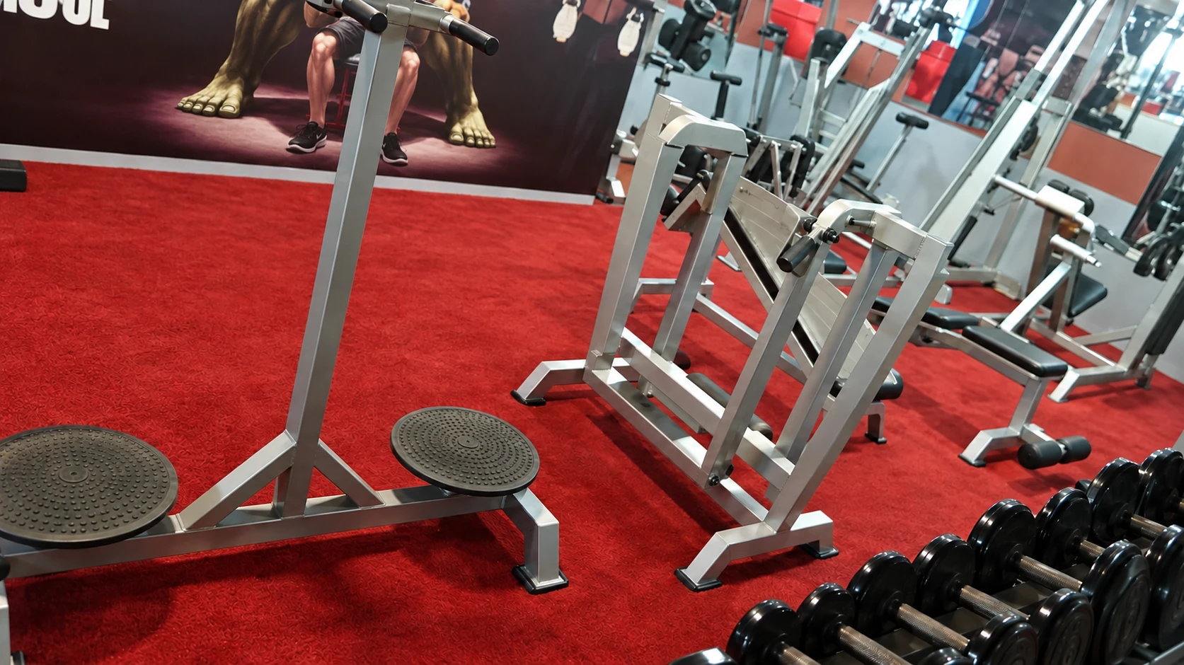 Strength machines, a bench and a rack of dumbbells inside New Gold Gym.